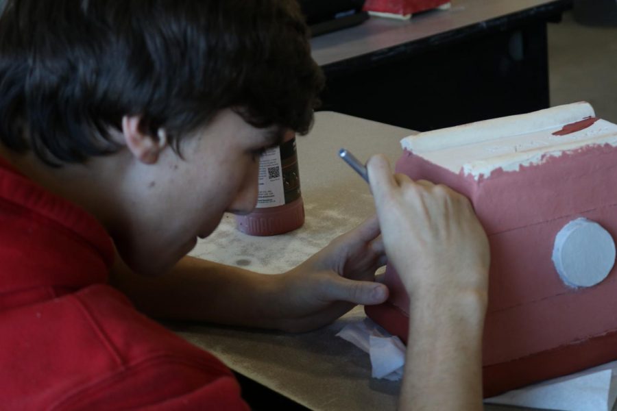 Ryan Moore ’20 cleans up his carved lines after glazing his piece.  “I don’t paint, I glaze” said Moore.  